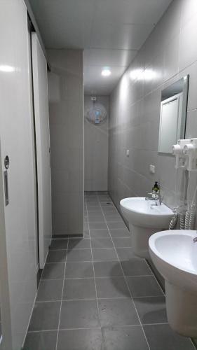 a bathroom with two sinks and a toilet and a mirror at Temple Side Hostel in Tainan