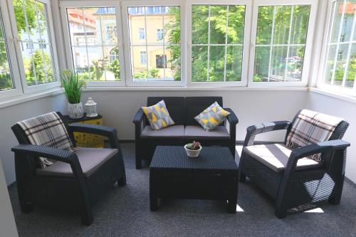 a living room with chairs and a couch and windows at Willa Scandia in Duszniki Zdrój