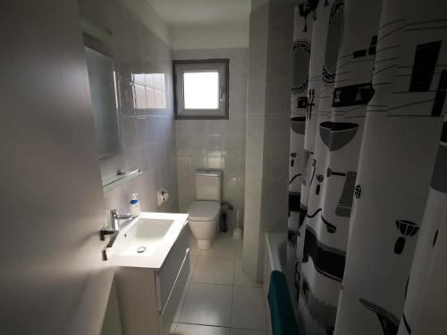 a bathroom with a sink and a toilet and a window at King Alexander Villa 22 in Paphos City