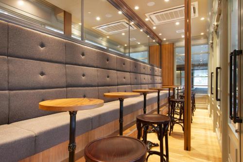 a row of tables and stools in a restaurant at Hotel Agora Osaka Moriguchi in Osaka