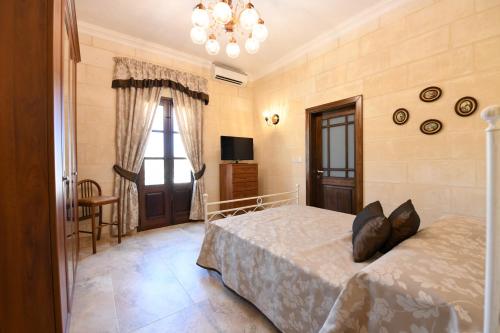a bedroom with a bed and a chandelier at Ir- Razzett t'Indri in Qala