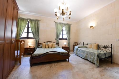 a bedroom with two beds and two windows at Ir- Razzett t'Indri in Qala