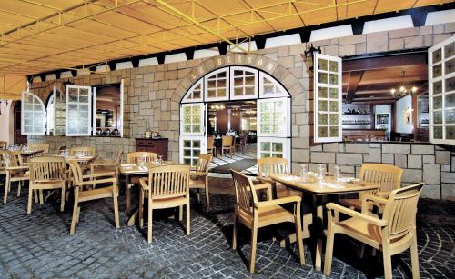 a restaurant with wooden tables and chairs and a brick wall at Colmar Tropicale in Bukit Tinggi