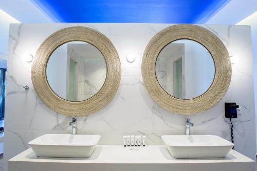 a bathroom with two sinks and two mirrors at Villaggio Boutique Hotel Hersonissos - Adults Only in Hersonissos