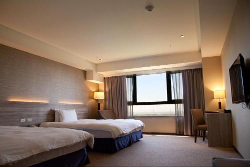 um quarto de hotel com duas camas e uma janela em Hotel Orchard Park - New Wing em Dayuan