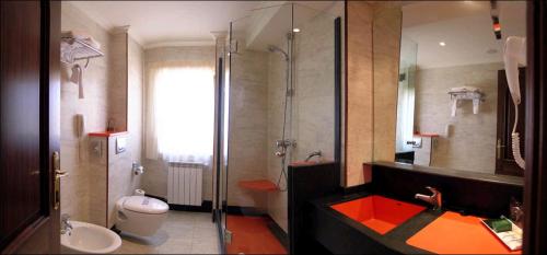 a bathroom with a toilet, sink, and shower at Hotel Sercotel Cuatro Postes in Ávila
