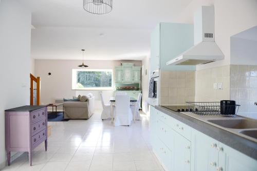 a kitchen with white appliances and a living room at La Ville Tanet in Landéhen