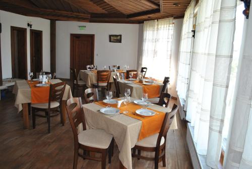 a dining room with tables and chairs and windows at Хотел Планински кът in Dorkovo