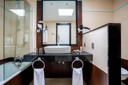 uma casa de banho com um lavatório, um espelho e uma banheira em Hotel Las Costas em Puerto del Carmen