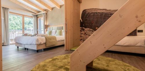 a bedroom with two beds and a wooden staircase at Hotel Val Di Sole in Mezzana