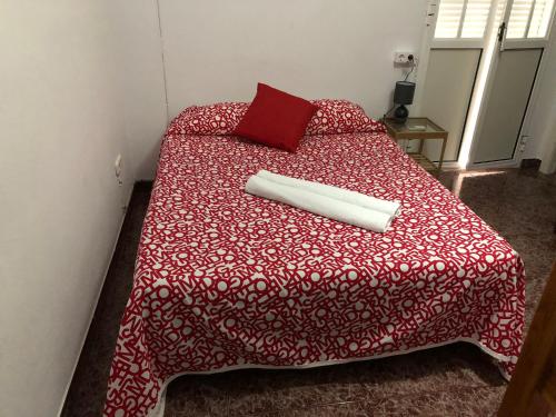 Una cama con un edredón rojo y una almohada. en Casa Antonio Algodonales, en Algodonales