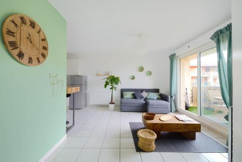 un salon avec un canapé et une horloge au mur dans l'établissement T2 cosy proche du centre-ville avec garage inclus, à Aix-en-Provence
