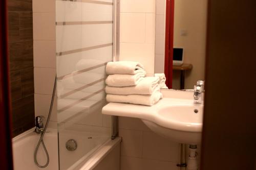 a bathroom with a sink and a shower and towels at Euro Hôtel Airport Orly Rungis in Fresnes