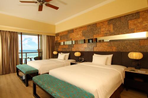 a hotel room with two beds and a balcony at The Bellevue Resort in Panglao