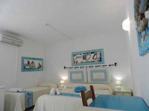 a bedroom with two beds and a blue table at Hotel Canne al Vento in Santa Teresa Gallura