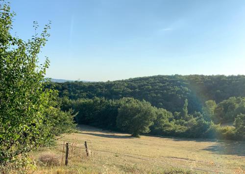 a field with a fence and trees in the background at La Meyssonnié in Damiatte
