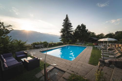 a swimming pool with chairs and an umbrella at Lamberthof in Montagna