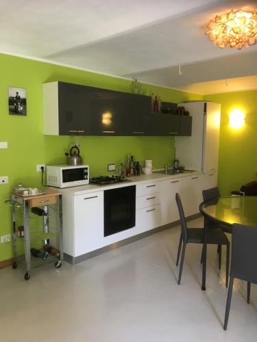 a kitchen with green walls and a table with a microwave at cascina Filura in Mango