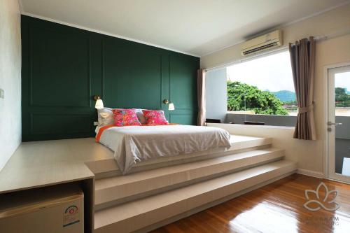 金三角Buakham Rim Khong บัวคำริมโขง的一间卧室设有绿色的墙壁和一张带红色枕头的床