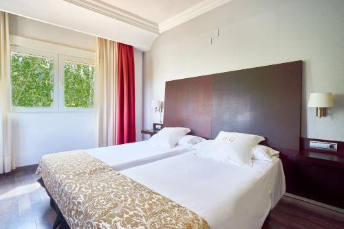 a hotel room with two beds and a window at Crisol Guadalupe in Granada