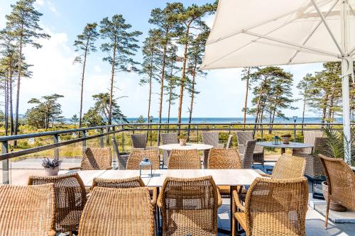 a patio with tables and chairs and an umbrella at Hotel Riviera Strand in Båstad