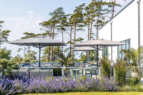 a patio with umbrellas and tables and purple flowers at Hotel Riviera Strand in Båstad
