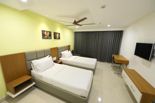 a hotel room with two beds and a television at Hotel Sri Ram Grand in Vijayawāda