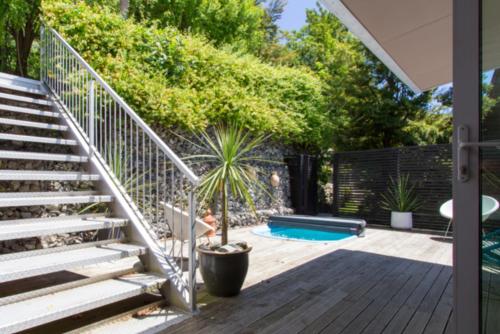 a patio with stairs and a pool with a palm tree at Treehouse Spa Escape - Private Spa Pool in Queenstown