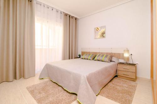 a white bedroom with a bed and a window at Espanatour TORREMAR in La Mata