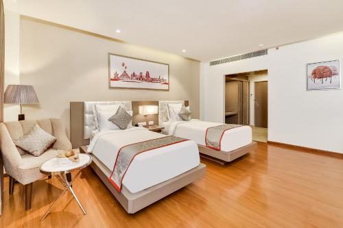 two beds in a room with a chair and a couch at Ramada by Wyndham Bengaluru Yelahanka in Yelahanka