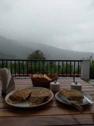 a wooden table with two plates of food on it at Enchanted Hills Farmstay in Mukteswar