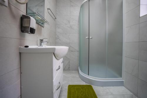 a white bathroom with a sink and a shower at Hotel Darina Tarnaveni in Tîrnăveni