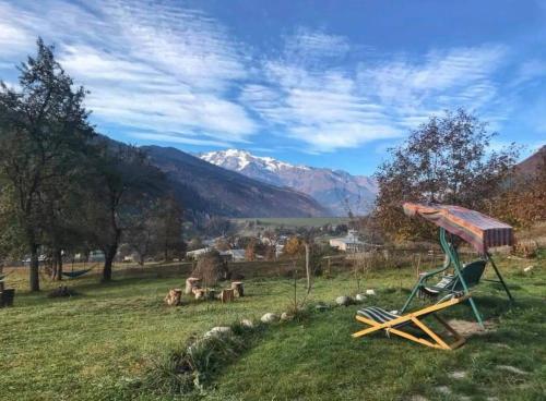 a playground in a field with mountains in the background at Roza's guest house in Mestia