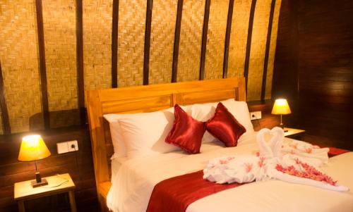 a bedroom with a bed with red and white pillows at Agasta Villa in Nusa Penida