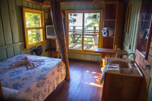 a bedroom with a bed and a sink and a window at Pousada Estação Baleia in Praia do Rosa