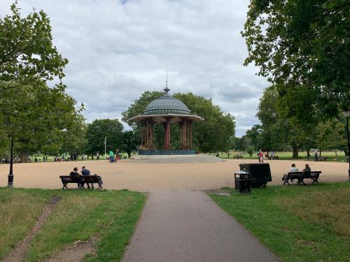 people sitting on benches in a park with a gazebo at WelcomeStay Clapham Junction 2 Bedroom Apartment in London