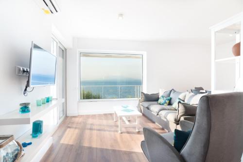 a living room with a couch and a large window at Epipleon suites in Áyioi Apóstoloi