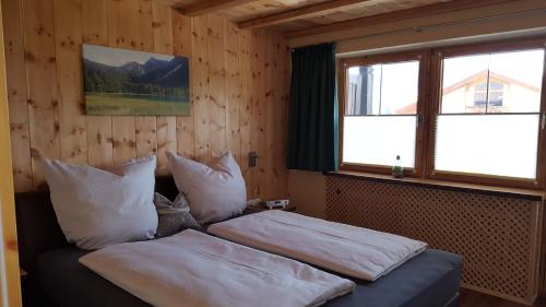ein Schlafzimmer mit einem Bett mit Kissen und einem Fenster in der Unterkunft Ferienwohnung Zirbenduft in Inzell
