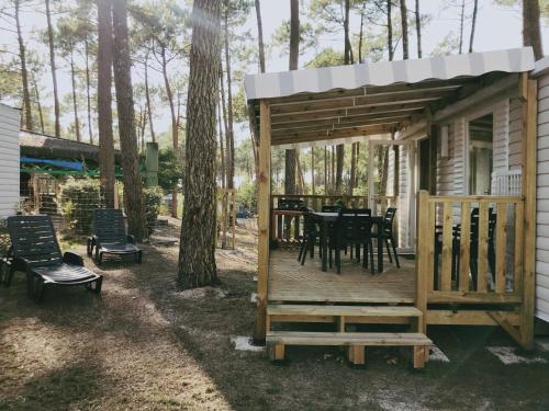 ein Haus mit einer Terrasse mit einem Tisch und Stühlen in der Unterkunft Mobilhome tout confort - Les dunes de Contis in Saint-Julien-en-Born