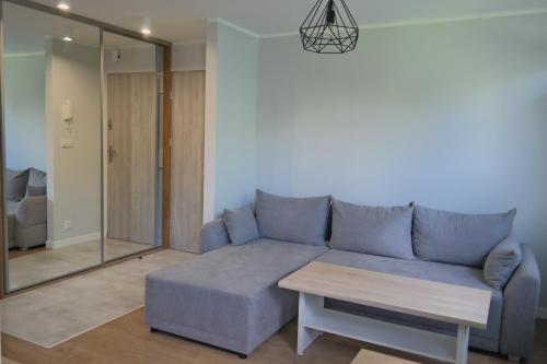 ein Wohnzimmer mit einem blauen Sofa und einem Tisch in der Unterkunft Apartament Bema in Białystok