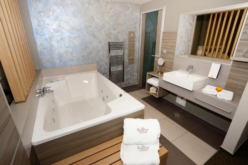 a bathroom with a large tub and a sink at Terme Paradiso - Hotel Paradiso in Dobova