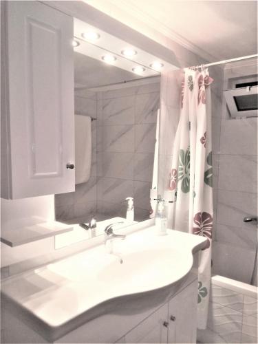 a white bathroom with a sink and a mirror at Grammatoula Apartment in Nikiana