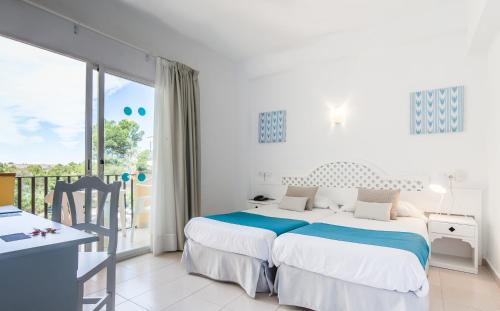 a white bedroom with two beds and a balcony at BLUESEA Costa Verde in El Arenal