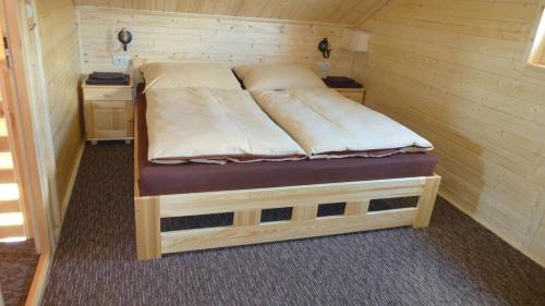 łóżko w drewnianym pokoju z dwoma bagażnikami w obiekcie Rekreačné chaty Bedolandia w Sławkowie Wielkim
