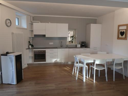 una cucina bianca con tavolo e sedie bianchi di Appartamento per vacanze "IL GELSO" a Rovereto