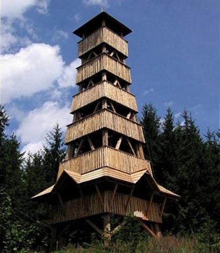 a tall wooden tower with trees in the background at Apartment WELLNESS Vlčková in Vlčková
