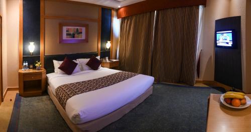 a hotel room with a large bed and a television at Juffair Grand Hotel in Manama