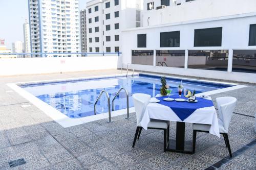 a table and chairs next to a swimming pool at The Juffair Grand Hotel in Manama