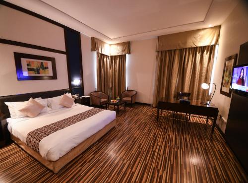a hotel room with a bed and a desk and a television at Juffair Grand Hotel in Manama