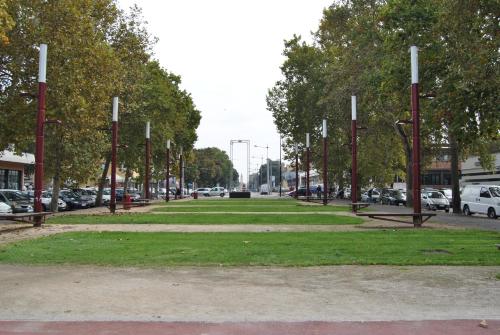 a park with red poles and green grass and cars at Lombardi Fleming in Parma